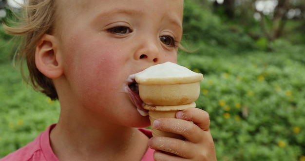 menino infantil segurando o cone de waffle apreciando sorvete de baunilha ao ar livre