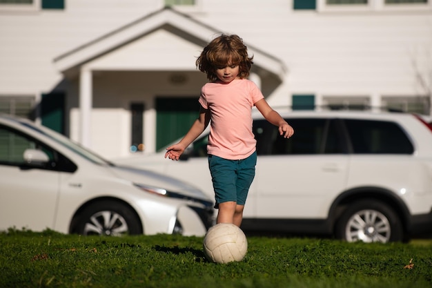 Menino jogador de futebol chutando futebol no campo de esportes crianças ativas futebol infantil