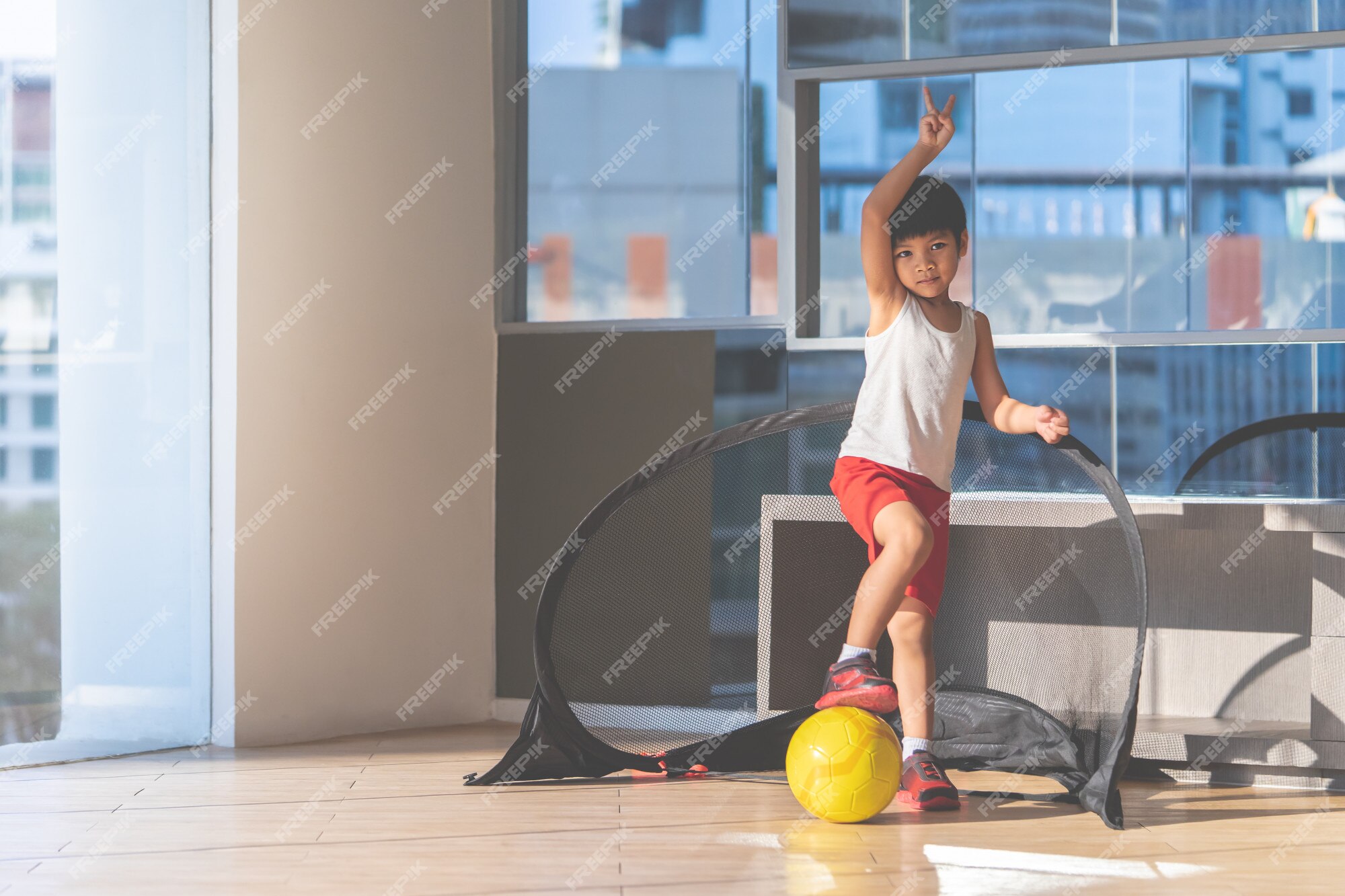 O Menino Do Jogador De Futebol Está Pisando Na Bola Na Sala Foto