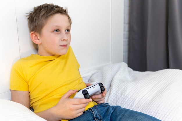 Menino jogando videogame deitado na cama