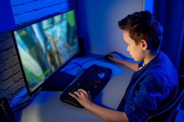 Menino jogando videogame em casa. Adolescente sério no computador. Viciado em videogame em casa.