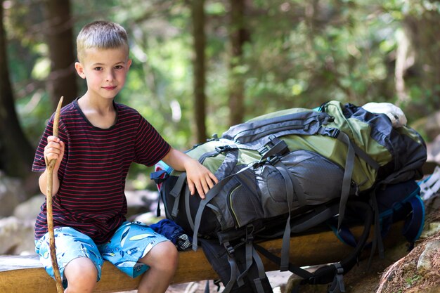 Menino jovem criança bonito com vara sentado sozinho na mochila grande turista