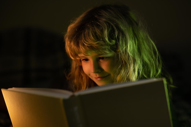 Menino lendo história de ninar foto do quarto escuro Criança lendo um livro mágico na cama Menino lendo livros em casa