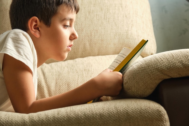 Menino lendo um livro deitado no sofá