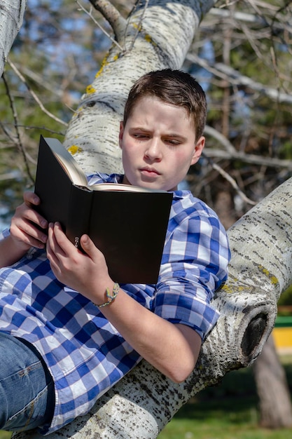 Menino lendo um livro na floresta com profundidade de campo e espaço para cópia