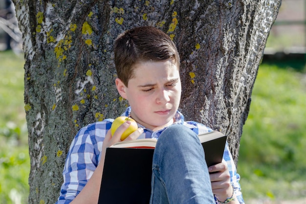 Menino lendo um livro na floresta com profundidade de campo e espaço para cópia