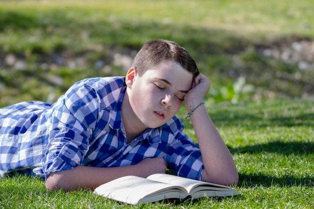 Menino lendo um livro na floresta com profundidade de campo e espaço para cópia