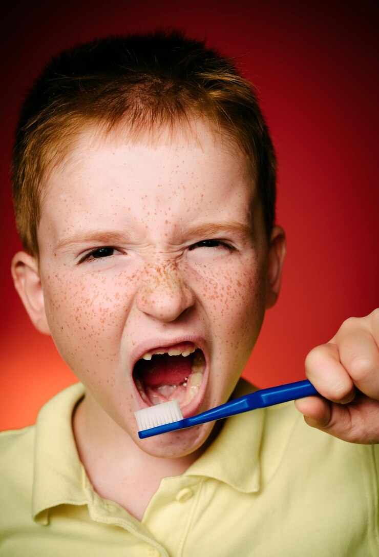 Foto menino limpa os dentes com escova de dentes design de camisa saúde higiene bucal menino sorridente com escoba de dentes na mão isolado em fundo vermelho menino feliz escovando os dentes