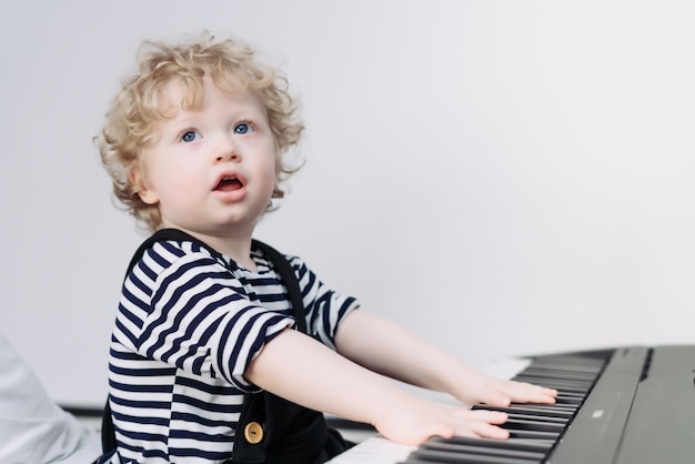 Menino loiro bonito tocando piano estudando o mundo