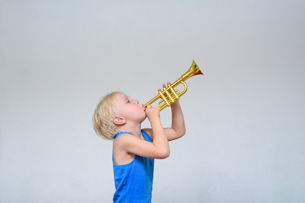 Menino loiro bonito tocando trompete de brinquedo