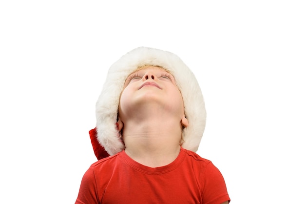 Menino loiro com chapéu de Papai Noel está olhando para cima Isolar