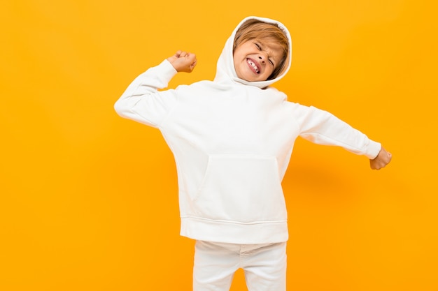 Foto menino loiro com um capuz branco gritando em voz alta na laranja