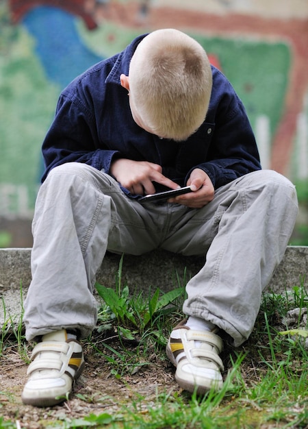 menino loiro jogando videogame ao ar livre no parque