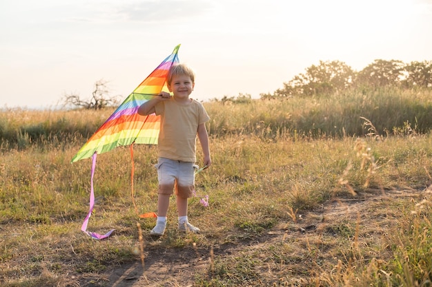 Menino menino feliz se divertindo com pipa na natureza ao pôr do sol