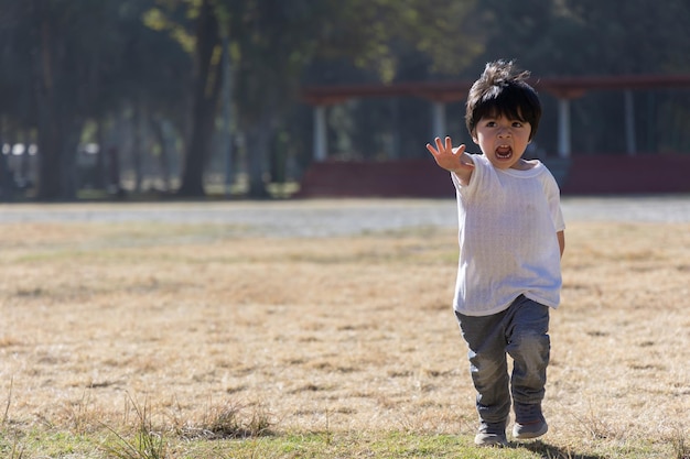 Menino mexicano de três anos brincando e correndo no parque