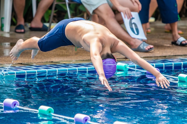 Menino nadador pulando a cabeça primeiro na piscina para nadar