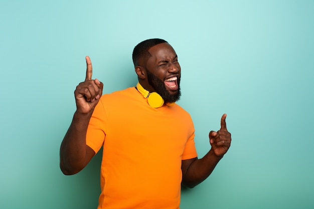 Menino negro com fone de ouvido amarelo ouve música e dança