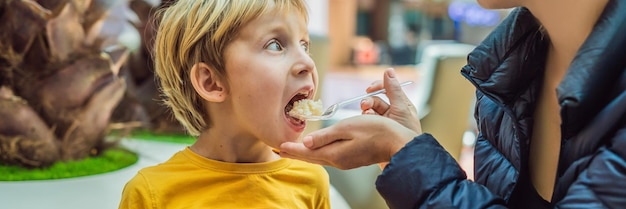 Menino no aeroporto, menino comendo comida enquanto espera seu formato longo de banner de voo