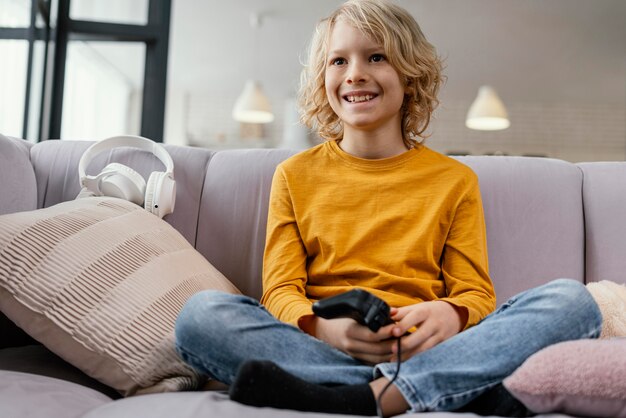 Menino no sofá com joysticks tocando