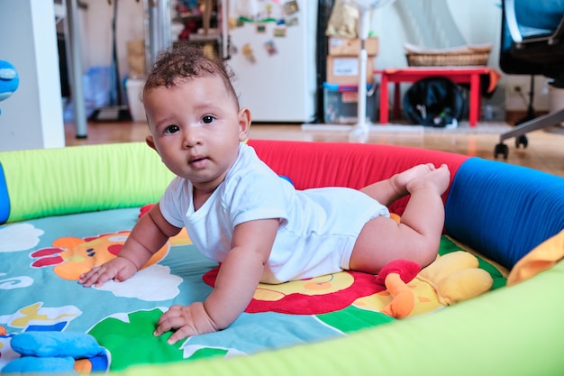 Menino olhando para a câmera enquanto estava deitado de bruços em uma esteira colorida.