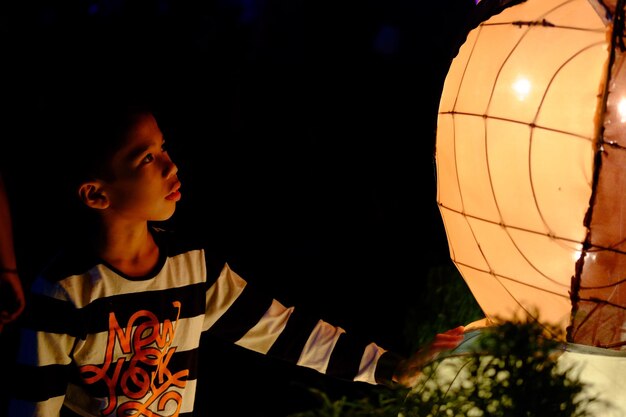 Menino olhando para uma lanterna iluminada durante a noite