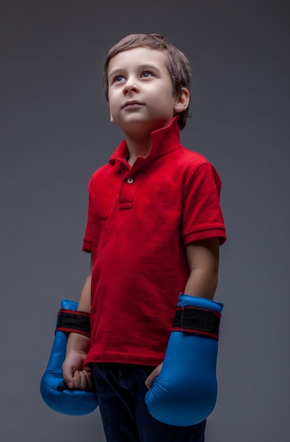 Foto menino pensativo posando em luvas de boxe