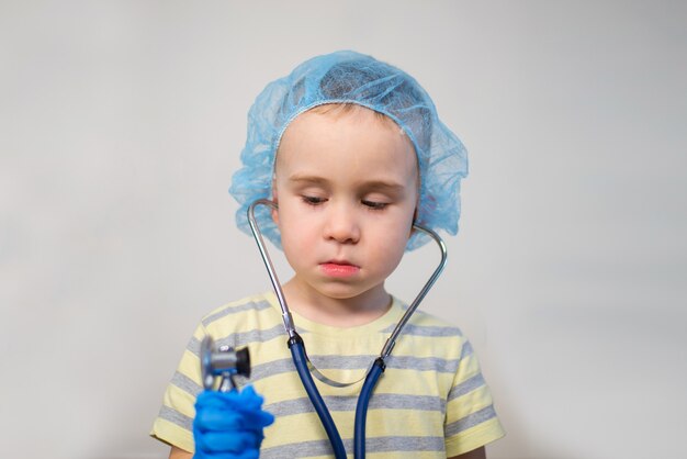 Menino pequeno, brincando de médico com estetoscópio