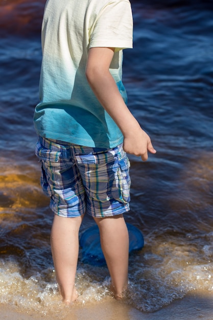 Menino pequeno fica com uma rede de pesca diretamente no mar.