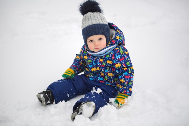 Menino pequeno na neve do inverno.