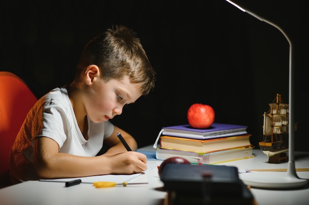 Menino pintando em um quarto escuro no final da tarde