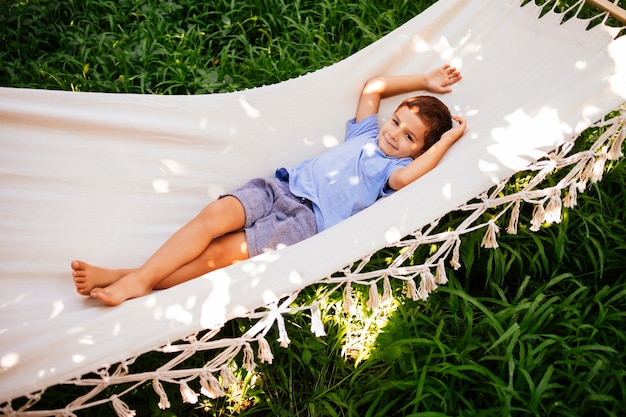 Foto menino pré-escolar deitado em uma rede branca