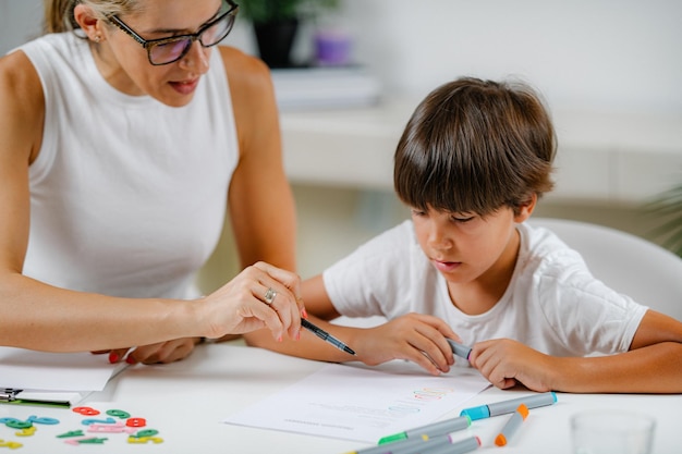 Menino pré-escolar fazendo teste de avaliação de educação escolar Psicólogo fazendo perguntas e menino pré-escolar escrevendo respostas