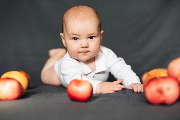 Menino recém-nascido deitado com maçãs. Criança caucasiana