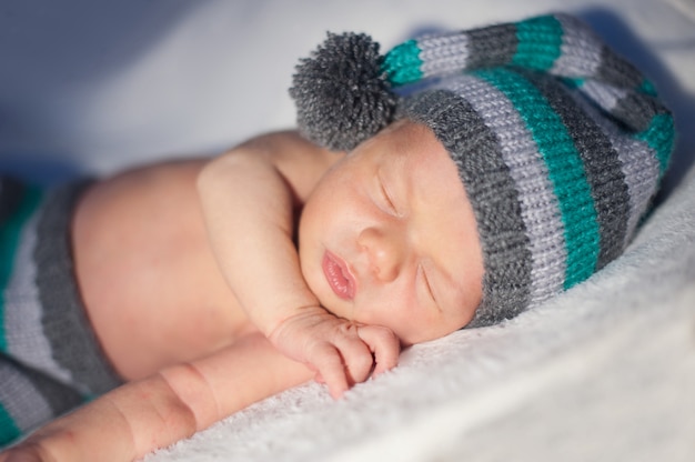 Foto menino recém-nascido dorme em um boné de malha