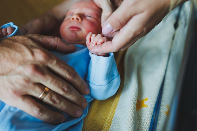 Foto menino recém-nascido nos braços de sua mãe e pai deitados em seus braços closeup vista superior jovens pais seguram seu bebê estilo de vida saudável paternidade