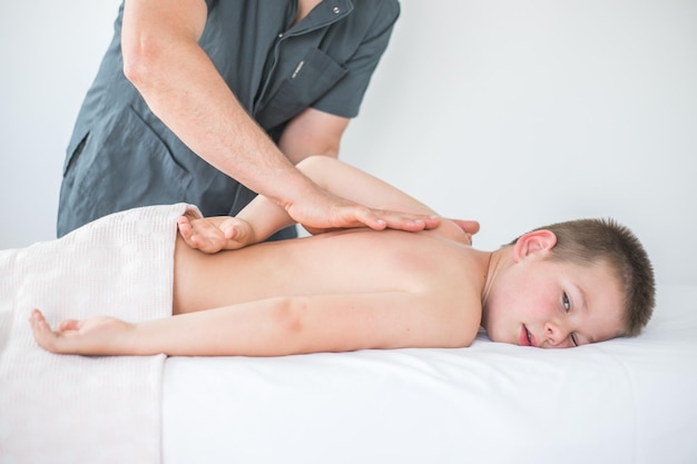 Menino relaxa de uma massagem terapêutica Fisioterapeuta trabalhando com paciente na clínica para tratar as costas de uma criança