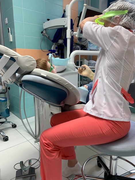 Menino ruivo criança veio ao dentista para um exame médico de tratamento de cárie de cuidados orais fazendo um procedimento odontológico