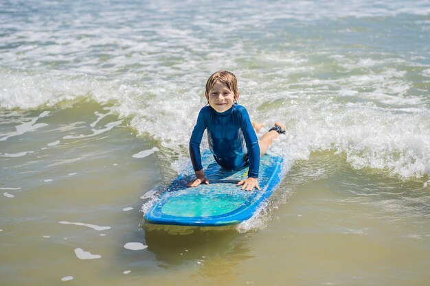 Menino saudável aprendendo a surfar no mar ou oceano