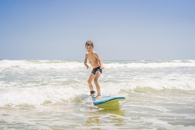 Menino saudável aprendendo a surfar no mar ou oceano