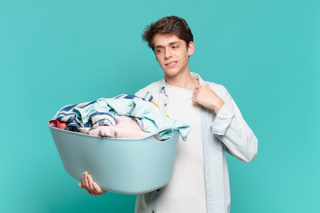 Menino se sentindo estressado, ansioso, cansado e frustrado, puxando a gola da camisa, parecendo frustrado com o conceito de problema em lavar roupas