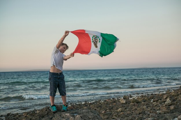 Menino segurando a bandeira do México no mar. 16 de setembro, Dia da Independência do México