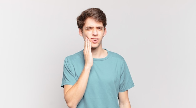 Menino segurando a bochecha e sofrendo de dor de dente, sentindo-se doente, infeliz e infeliz, procurando um dentista