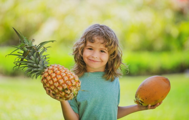 Menino segurando abacaxi e coco sorrindo com uma carinha feliz frutas de verão