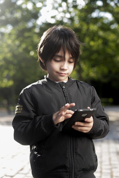 menino segurando o telefone celular no parque