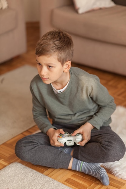 Menino segurando um controle remoto de videogame na sala de estar em casa