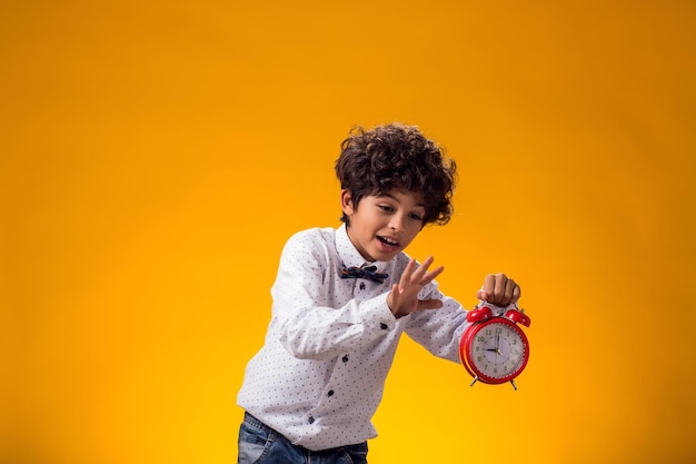 Foto menino segurando um despertador sobre fundo amarelo conceito de gerenciamento de tempo