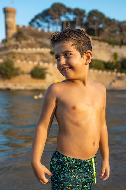 Foto menino sem camisa de pé ao lado da água ao ar livre