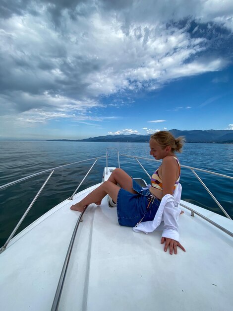 Menino sentado em um barco no mar contra o céu