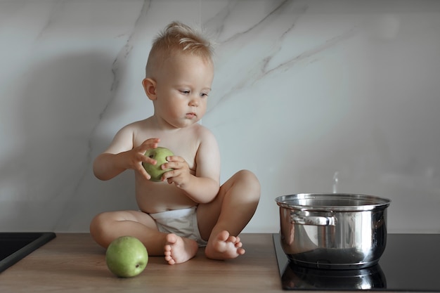 Foto menino sentado na bancada da cozinha com maçãs verdes