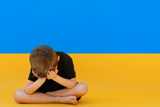 Menino sentado na bandeira da Ucrânia